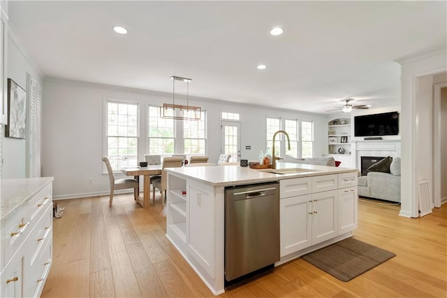 kitchen with stainless steel dishwasher, sink, decorative light fixtures, a center island with sink, and white cabinetry