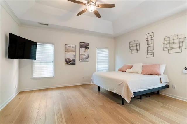 bedroom with a raised ceiling, ceiling fan, light hardwood / wood-style flooring, and ornamental molding