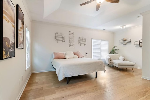 bedroom featuring a tray ceiling, ceiling fan, light wood-type flooring, and ornamental molding