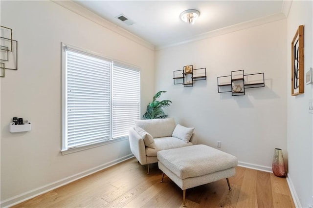 living area with ornamental molding, light hardwood / wood-style flooring, and a healthy amount of sunlight