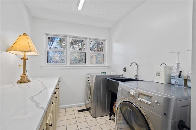 laundry area with cabinet space, light tile patterned floors, independent washer and dryer, a textured ceiling, and a sink