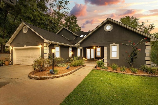 view of front facade featuring an attached garage, driveway, french doors, and stucco siding