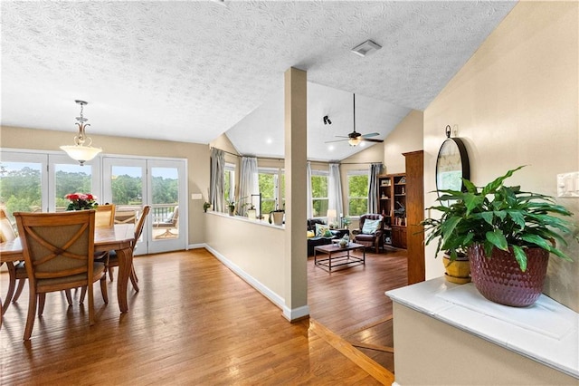 dining space with lofted ceiling, a ceiling fan, a textured ceiling, wood finished floors, and baseboards