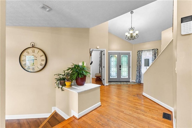 entrance foyer with baseboards, vaulted ceiling, wood finished floors, and french doors