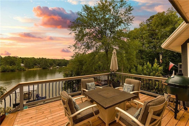 deck at dusk with a water view and outdoor dining space