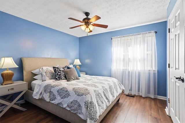 bedroom with a ceiling fan, wood-type flooring, visible vents, and a textured ceiling