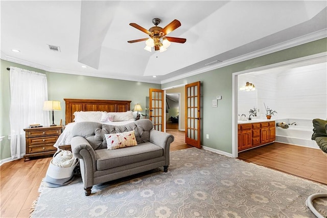 bedroom featuring light wood finished floors, visible vents, ornamental molding, a tray ceiling, and french doors