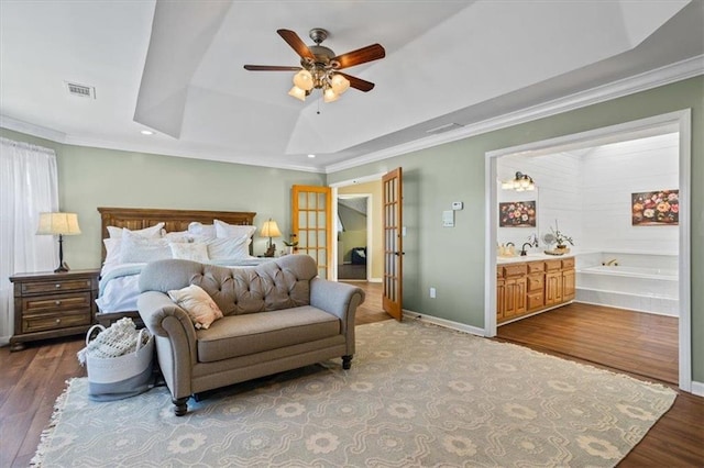 bedroom featuring a raised ceiling, visible vents, baseboards, and wood finished floors