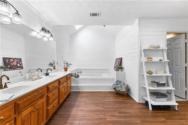 bathroom featuring a textured ceiling, wood finished floors, a sink, and visible vents