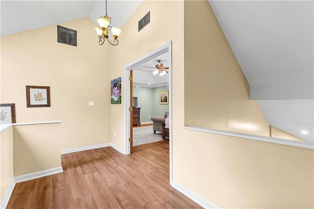 hall featuring visible vents, vaulted ceiling, baseboards, and wood finished floors