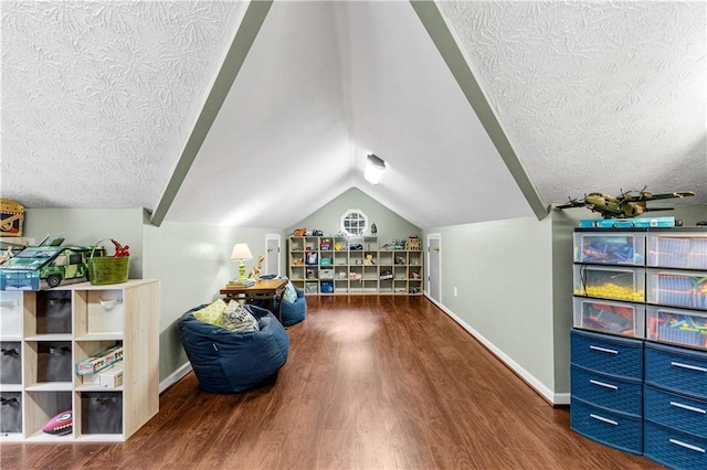 interior space with vaulted ceiling, a textured ceiling, wood finished floors, and baseboards