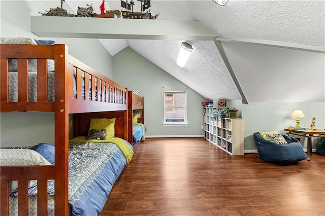 bedroom with lofted ceiling, a textured ceiling, and wood finished floors