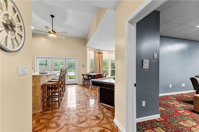 interior space featuring a paneled ceiling, ceiling fan, and baseboards