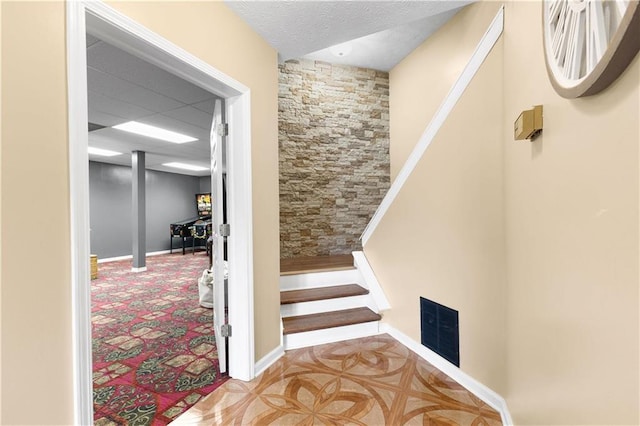 stairs featuring baseboards, visible vents, and a textured ceiling