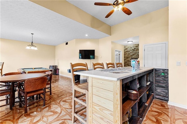 kitchen with baseboards, a kitchen breakfast bar, a textured ceiling, and a center island