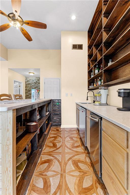 interior space with baseboards, visible vents, a ceiling fan, dishwasher, and a sink