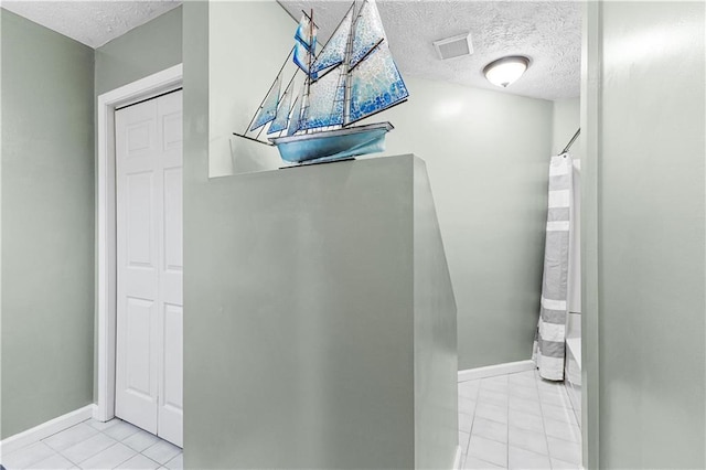 bathroom with baseboards, visible vents, a textured ceiling, and tile patterned floors