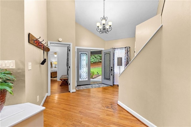 entrance foyer featuring baseboards, high vaulted ceiling, light wood finished floors, and a notable chandelier