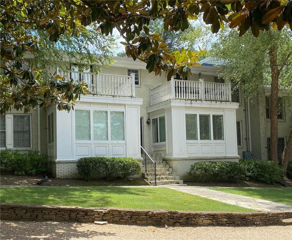 exterior space featuring a front lawn and a balcony