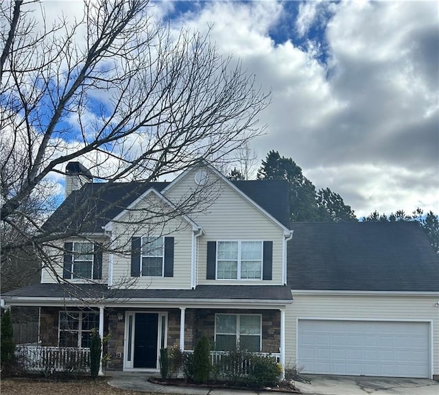 traditional-style home featuring a porch, an attached garage, stone siding, concrete driveway, and a chimney