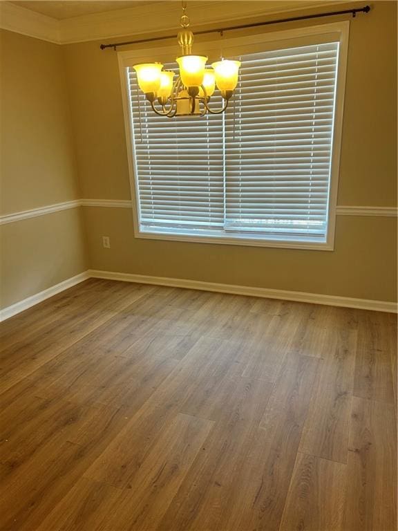 unfurnished room with a chandelier, wood finished floors, and baseboards