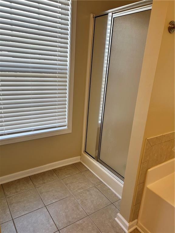 full bathroom featuring tile patterned flooring, a shower stall, baseboards, and a bath