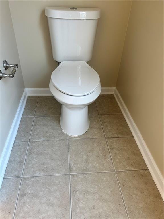 bathroom featuring tile patterned flooring, baseboards, and toilet