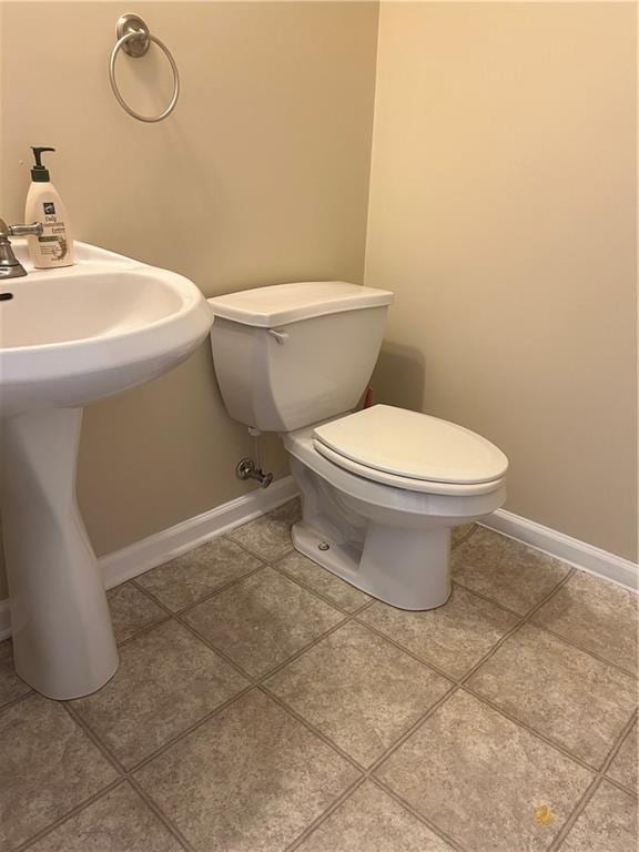 half bathroom with tile patterned flooring, baseboards, and toilet