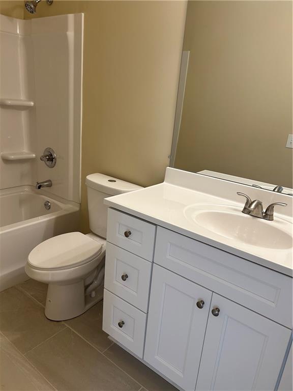 bathroom with tile patterned flooring, shower / tub combination, vanity, and toilet