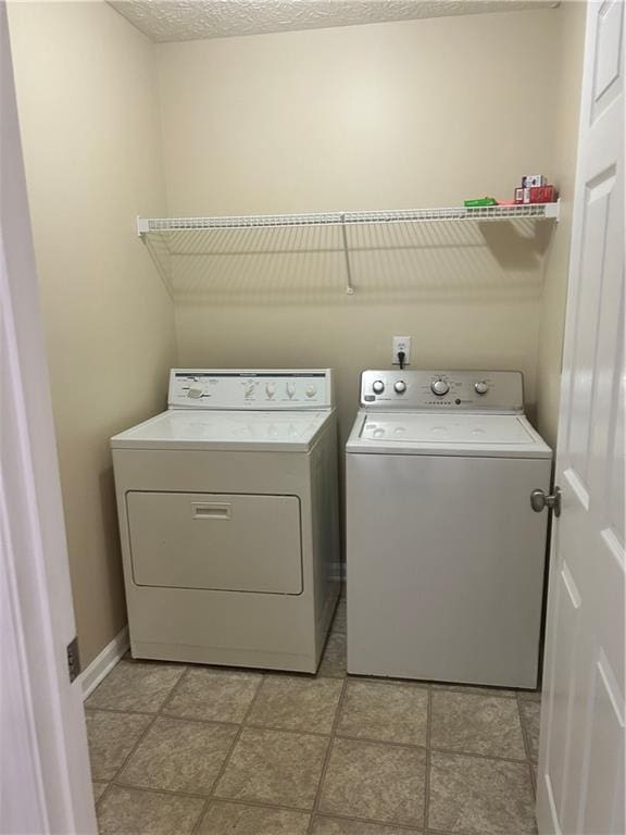 clothes washing area featuring laundry area, independent washer and dryer, a textured ceiling, and baseboards