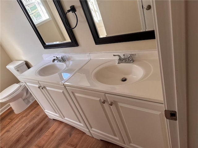 bathroom featuring a sink, toilet, wood finished floors, and double vanity