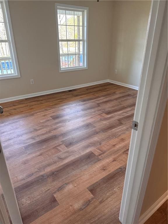 unfurnished room with visible vents, dark wood-type flooring, and baseboards