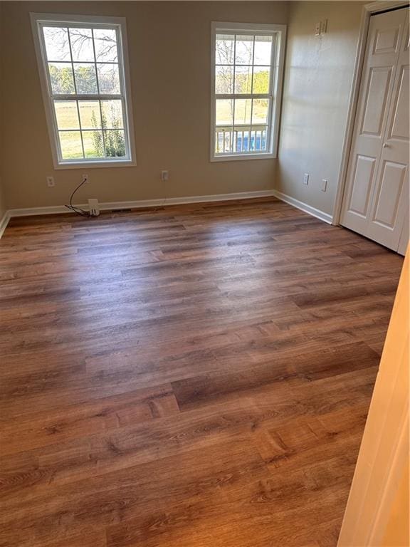 empty room featuring baseboards and dark wood-style flooring