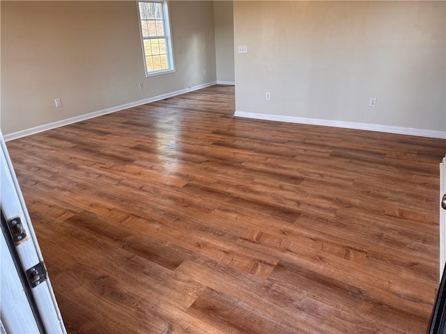 empty room featuring dark wood-type flooring and baseboards