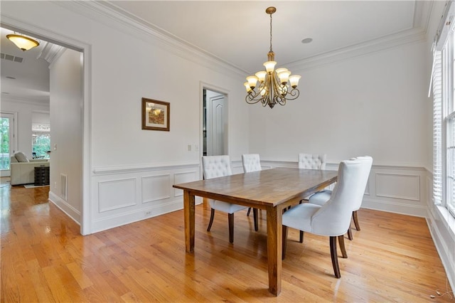 1003 Pearl Pt NE, Sandy Springs, GA 30328 - dining room featuring a chandelier, crown molding, light wood-type flooring, a wainscoted wall, and a decorative wall