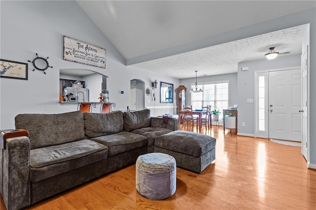 living room with high vaulted ceiling, light hardwood / wood-style floors, and a notable chandelier