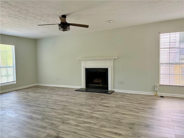 5105 N Bridges Dr, Alpharetta, GA 30022 - unfurnished living room with wood finished floors, a ceiling fan, a fireplace with raised hearth, baseboards, and a textured ceiling