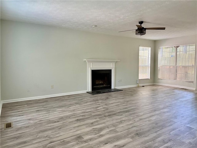 5105 N Bridges Dr, Alpharetta, GA 30022 - unfurnished living room with wood finished floors, a ceiling fan, a textured ceiling, baseboards, and a fireplace with raised hearth