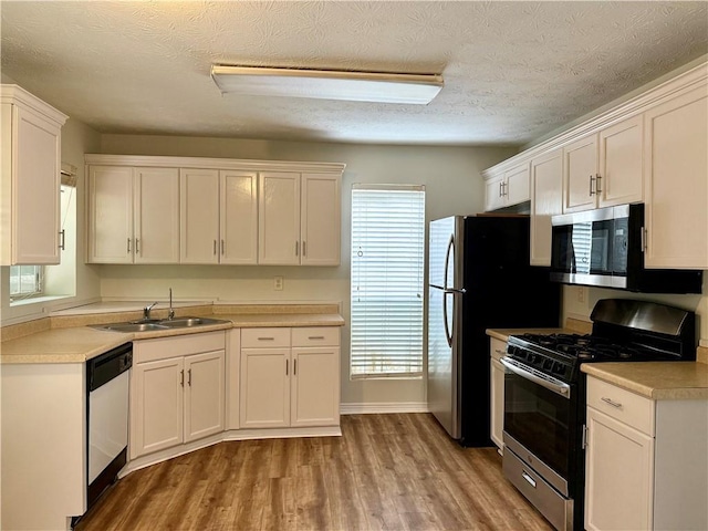 5105 N Bridges Dr, Alpharetta, GA 30022 - kitchen with appliances with stainless steel finishes, a sink, light wood-style floors, white cabinets, and light countertops