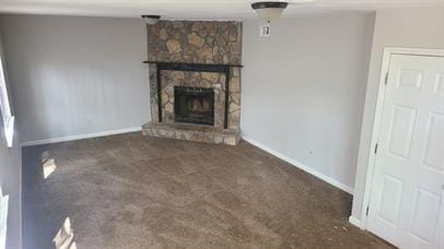 unfurnished living room featuring baseboards, carpet floors, and a stone fireplace