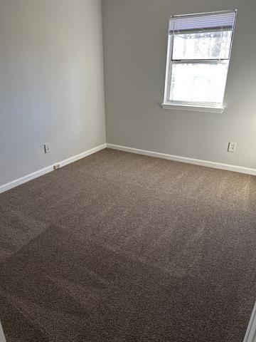 empty room featuring baseboards and dark carpet