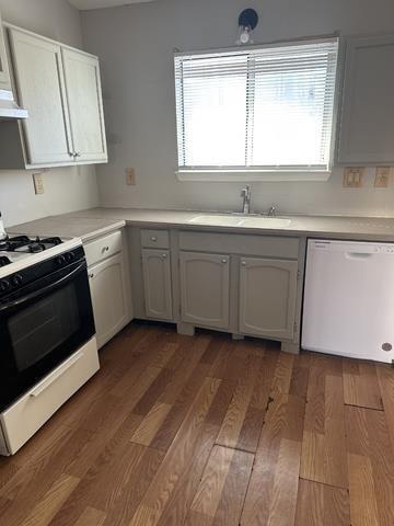 kitchen featuring white appliances, a sink, healthy amount of natural light, and light wood-style floors