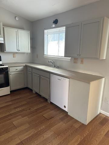 kitchen featuring white dishwasher, range with electric stovetop, a sink, dark wood-style floors, and light countertops