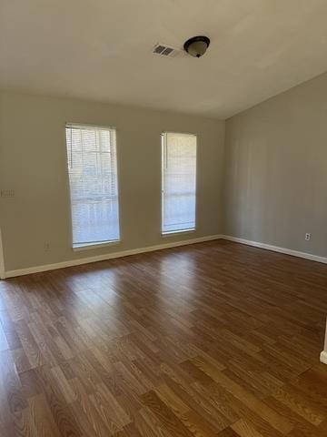 spare room featuring dark wood-type flooring and baseboards