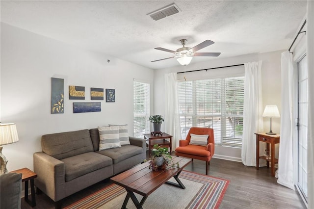 living room with ceiling fan, dark hardwood / wood-style floors, and a textured ceiling