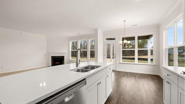 13917 Homer Ln, Covington, GA 30014 - kitchen featuring light countertops, a sink, a chandelier, a warm lit fireplace, and dishwasher