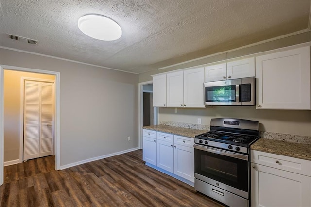 4650 Big Valley Ct, Stone Mountain, GA 30083 - kitchen with appliances with stainless steel finishes, a textured ceiling, dark wood-type flooring, white cabinets, and baseboards