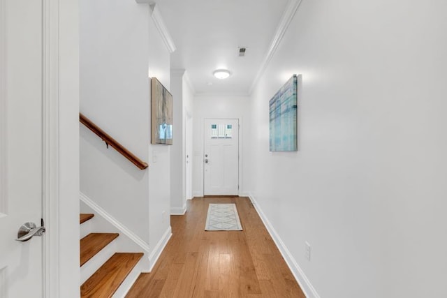 doorway with light wood-type flooring and ornamental molding