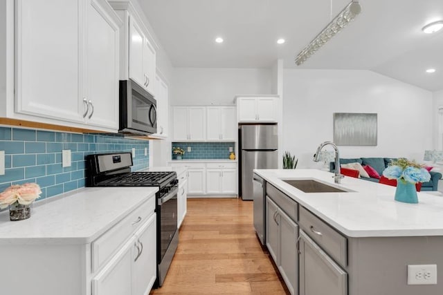 kitchen with tasteful backsplash, white cabinets, stainless steel appliances, light hardwood / wood-style floors, and sink