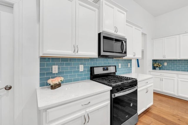 kitchen with tasteful backsplash, stainless steel appliances, light stone counters, light wood-type flooring, and white cabinetry